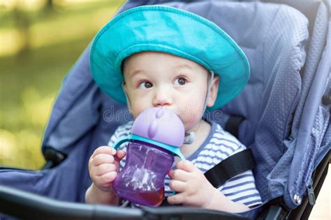 Baby Drinks From Bottle And Sitting In A Baby Carriage Stock Photo