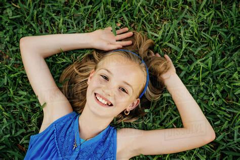 Close Up Portrait Of Smiling Caucasian Girl Laying On Grass Stock