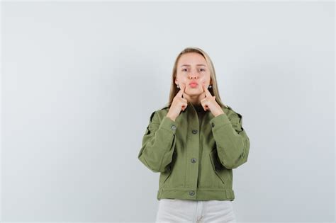 Free Photo Young Female Squeezing Her Cheeks In Green Jacketjeans