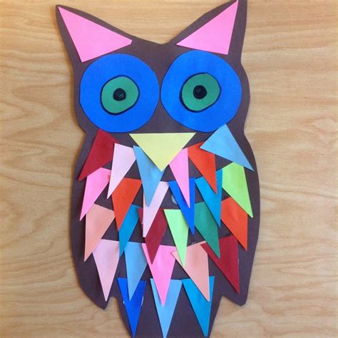 An Owl Made Out Of Colored Paper Sitting On Top Of A Wooden Table
