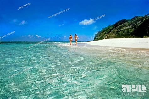 Two Women Walk Naked On The White Sand Caribbean Beach In The Tobago