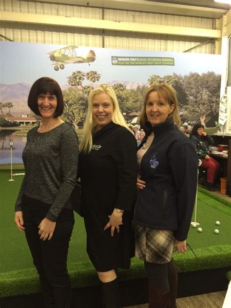 Three Women Standing Next To Each Other In Front Of A Golf Course
