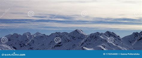 Snowy High Mountains And Sunlit Cloudy Sky At Winter Evening Stock