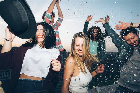 Group Of Friends Dancing Enjoying Roof Party Confetti In Air Stock