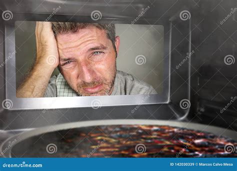 Messy And Funny Dummy Man In The Kitchen Looking Through Microwave Or