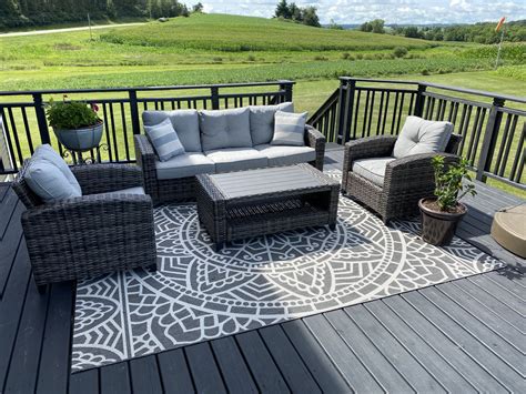 An Outdoor Deck With Wicker Furniture And Potted Plants On The Side