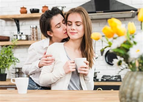 jovem lésbica mulher amando dela namorada segurando xícara café em mão foto grátis