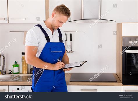 Young Repairman Writing On Clipboard Kitchen Stock Photo 561918415