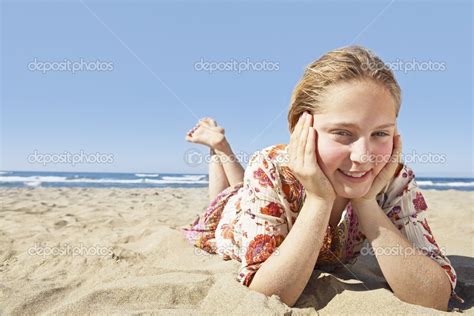 Girl Laying Down On A Golden Sand Beach Smiling At The Camera And
