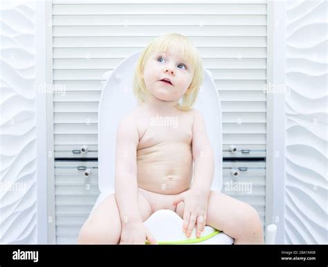 Ein Kleines Blondes Mädchen Mit Spitzbübischer Optik Sitzt Auf Der Toilette In Einem Hell