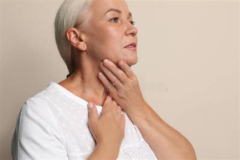 Mature Woman Doing Thyroid Self Examination On Beige Background Stock