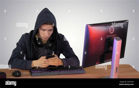 Hooded Hacker Using Laptop And Smartphone On Gradient Background Stock