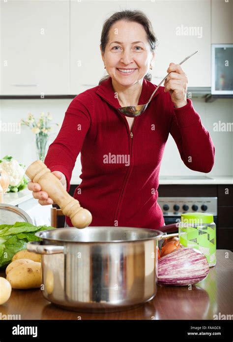 Happy Mature Woman Cooking Soup In Her Kitchen Stock Photo Alamy