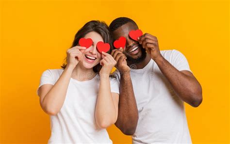 Romantic Multiracial Couple Posing With Red Hearts Over Eyes And