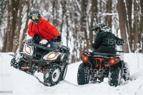 Riding The Opposite Ways Two People Are On The Atv In The Winter Forest