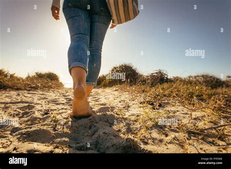 Low Angle Close Up Of A Woman Walking Bare Feet On Beach Sand Wearing A