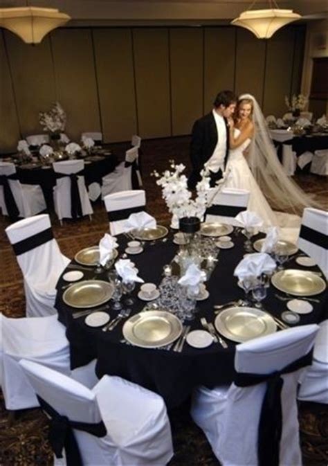 The niles chair is a small scale chair offering generous seating comfort and is covered in a contemporary silver gray and creamy white geometric links fabric. Black table cloth with white chair covers wth black sash ...