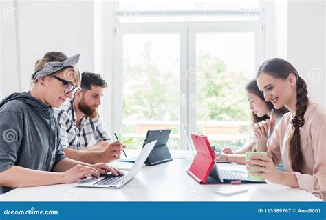 Dedicated Young People Sharing A Desk While Telecommuting Stock Image