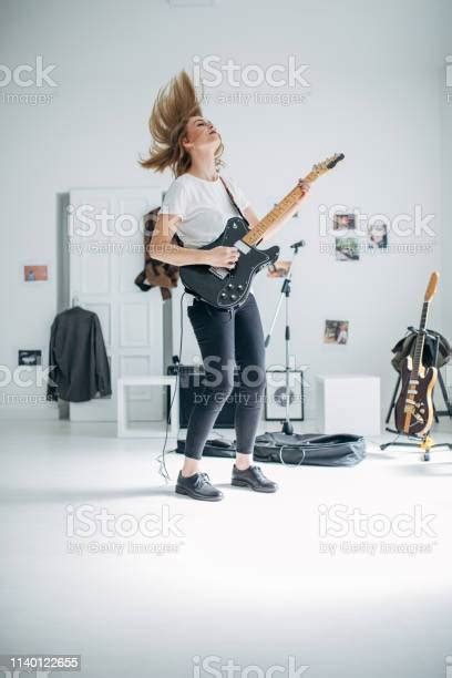 Blonde Woman Playing Electric Guitar In Music Studio Stock Photo