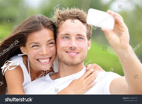 Couple Fun Taking Self Portrait Picture Photos With Mobile Smart Phone Or Pocket Camera Outdoors