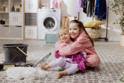 Premium Photo Smiling Sisters Sit On Laundry Room Floor Hugging Cooperation While Cleaning