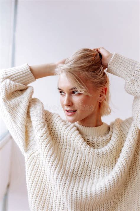 Appealing Woman Wearing Sweater Fixing Her Hair In The Morning Stock