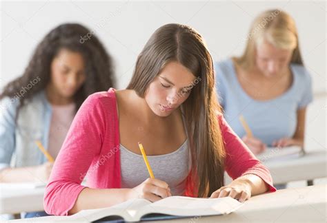 Teenage Students Writing In Book At Desk — Stock Photo © Tmcphotos
