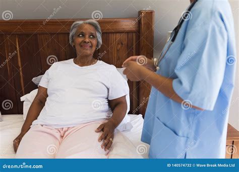 Senior Woman Interacting With Female Doctor In Bedroom Stock Photo