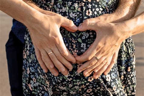 Man And Woman Holding Heart Shaped Hands On Her Pregnant Belly Stock