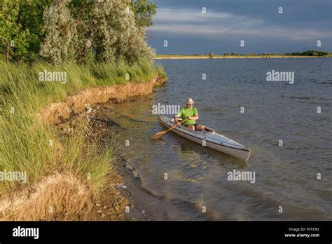 male paddler paddling a decked expedition canoe on a lake in northern