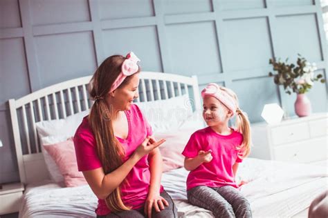 Girl And Her Mom Sitting On The Bed And Make Face Care Stock Image