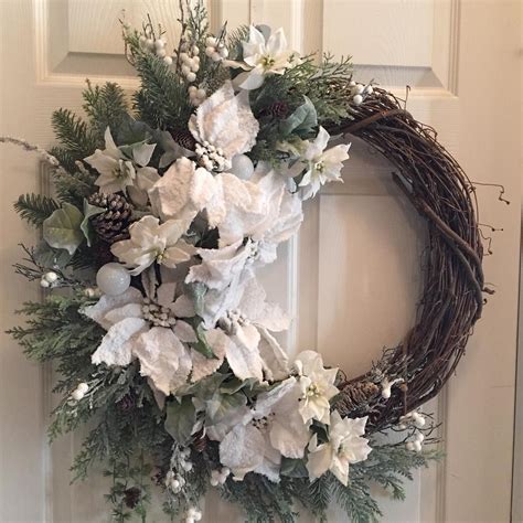 A Wreath With White Flowers And Greenery Hangs On The Front Door