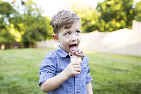 Preschool Boy Eating Ice Cream Cone In Summer Yard Stock Photo