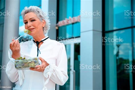 Mature Businesswoman Eating Salad In Front Of Office Building Stock