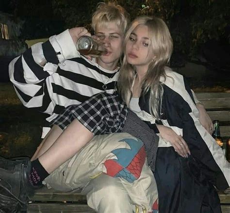 Two People Are Sitting On A Bench Drinking