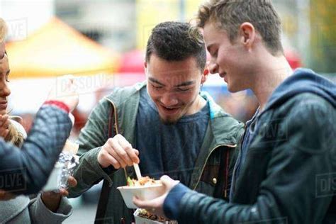 Group Of Young Adults Eating Takeaway Food Outdoors Stock Photo