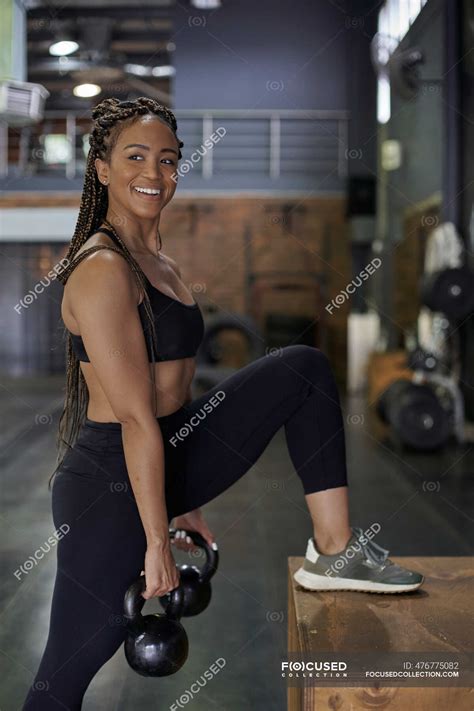 Smiling Female Athlete Lifting Kettlebells While Standing In Gym Adults South Africa Stock
