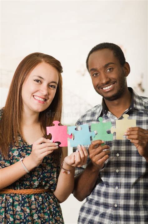 Interracial Charming Couple Wearing Casual Clothes Holding Up Large Puzzle Pieces And