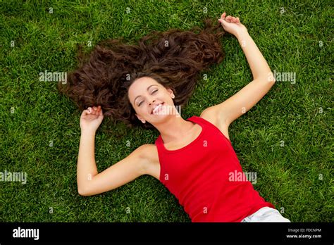 Outdoor Portrait Of A Beautiful Young Woman Lying On The Grass Stock