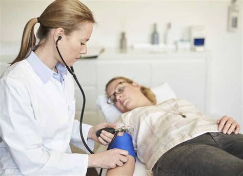 Female Doctor Taking Blood Pressure Of Patient In Medical Practice