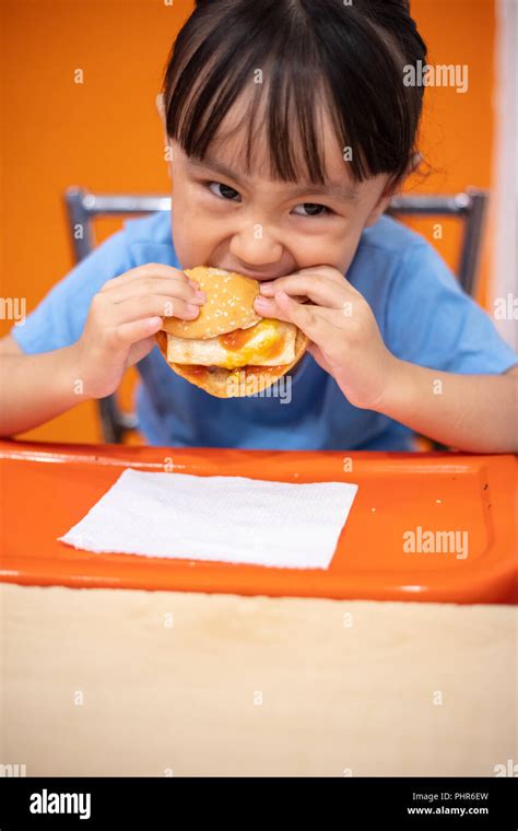 Chino Asia Niña Comiendo Hamburguesa En Un Restaurante Interior Fotografía De Stock Alamy
