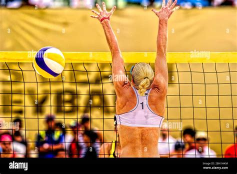 A Female Beach Volleyball Player Rises To Block The Ball At The Net