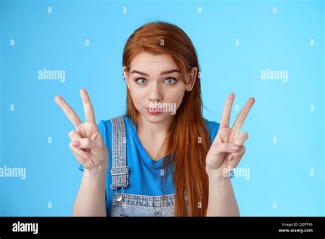 playful cute silly redhead girlfriend making funny face show peace victory signs hold breath