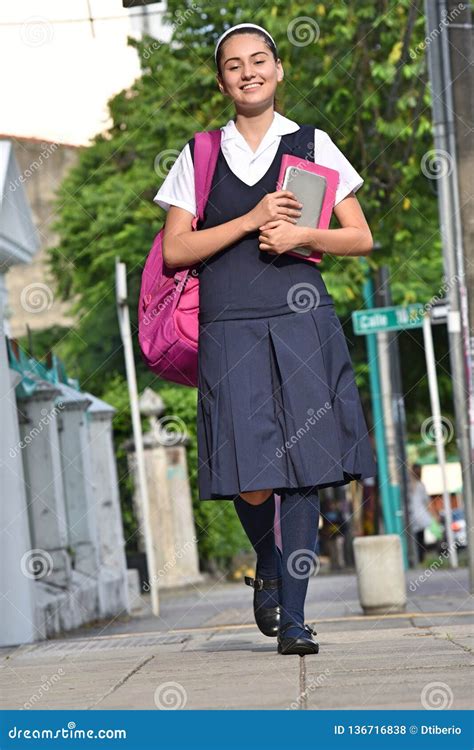 Female University Student Wearing Uniform Walking On Sidewalk Stock