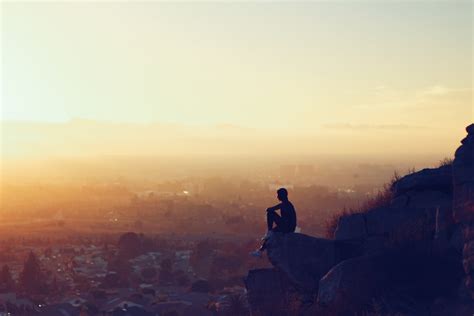 Landscape Silhouette Photography Of Person Sitting On Cliff Facing