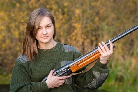 Portrait Of A Beautiful Young Girl In Camouflage Hunter With Shotgun