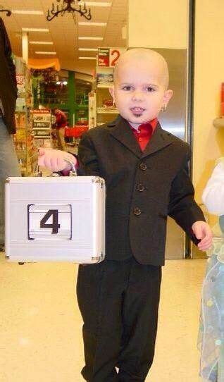 A Little Boy In A Suit And Tie Holding A Suitcase With The Number Four