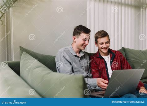 Two Teenage Guys Watching Funny Video At Laptop And Laughing Stock