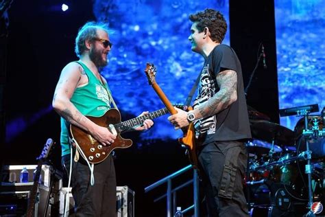 Two Men Are Playing Guitars On Stage