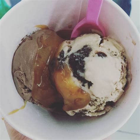 An Ice Cream Sundae With Caramel And Chocolate In A White Bowl On A Table